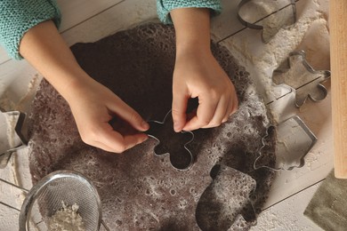 Little child making Christmas cookies at white wooden table, top view