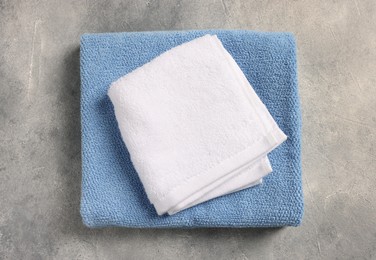 Photo of Soft folded terry towels on light gray textured background, top view