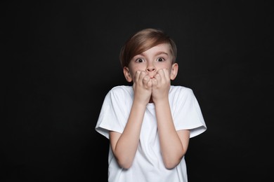 Photo of Little boy feeling fear on black background