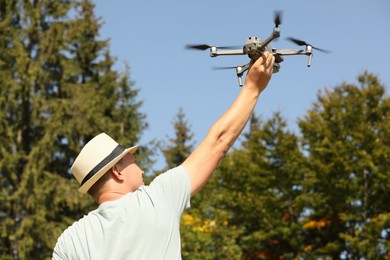 Man with drone outdoors on sunny day, back view