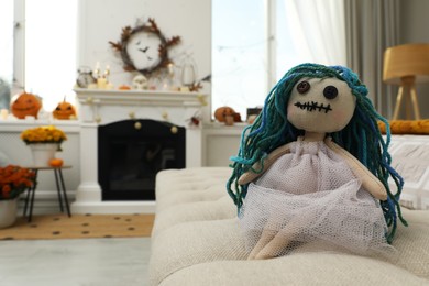 Spooky doll on sofa in room, space for text. Halloween decor
