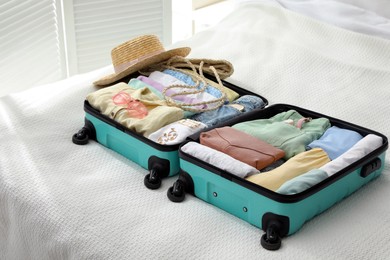 Open suitcase packed for trip and accessories on bed