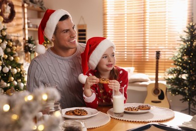 Happy father and his daughter with delicious Christmas cookies at home, space for text
