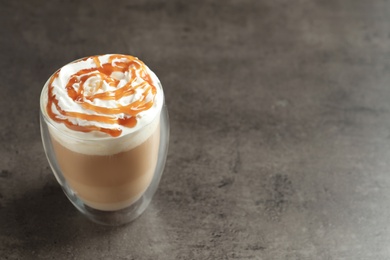 Glass with delicious caramel frappe on grey background