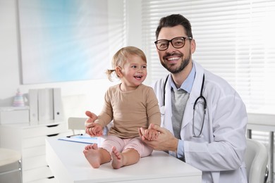 Pediatrician examining cute little baby in clinic