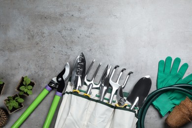 Flat lay composition with gardening tools and green plants on grey background, space for text