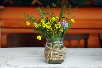 Bouquet of beautiful wildflowers in glass vase on table indoors