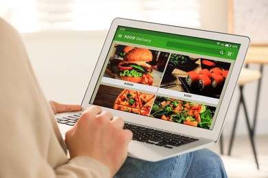 Man using laptop for ordering food online at home, closeup. Concept of delivery service