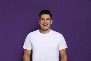 Handsome man laughing on purple background. Funny joke