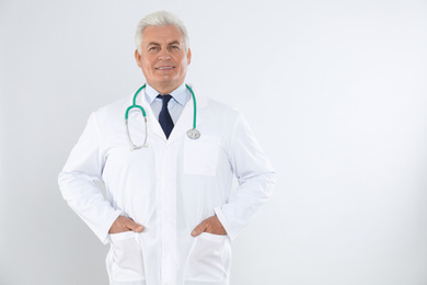 Photo of Portrait of senior doctor with stethoscope on white background