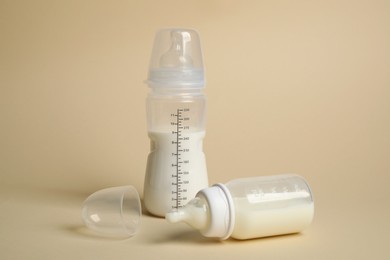 Photo of Feeding bottles with baby formula on beige background