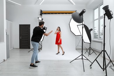 Photo of Professional photographer working with beautiful model in modern photo studio