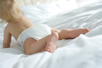 Cute little baby in diaper in bedroom, focus on legs