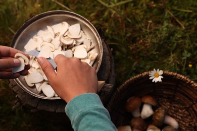 Man slicing freshly picked mushrooms outdoors, closeup