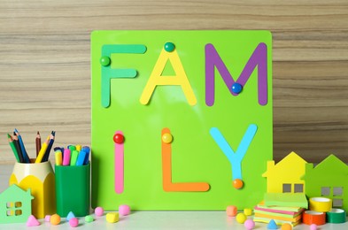 Magnetic board with text Family surrounded by different stationery on white table