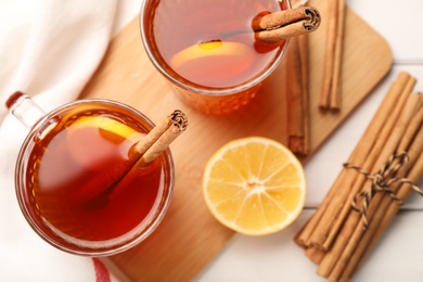 Delicious hot tea with cinnamon and lemon on white wooden table, flat lay