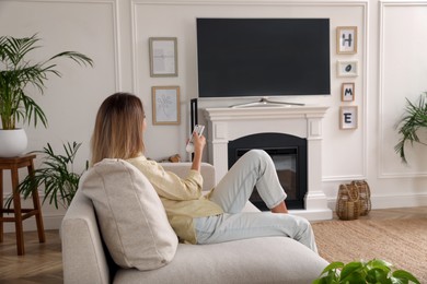 Young woman watching television at home. Living room interior with TV on fireplace