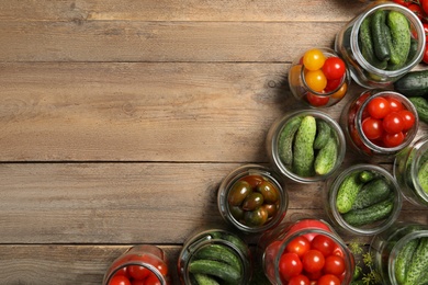 Pickling jars with fresh vegetables on wooden table, flat lay. Space for text