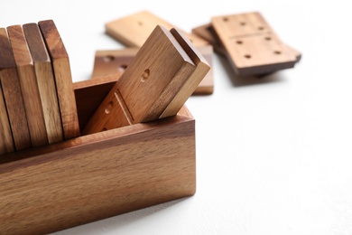Set of wooden dominoes in box on white table, closeup
