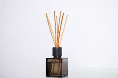 Photo of Aromatic reed freshener on table near white wall