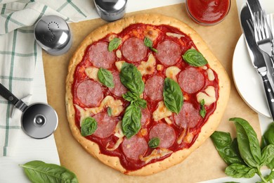 Photo of Pita pizza with pepperoni, cheese and basil on white wooden table, flat lay