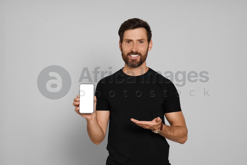 Happy man with smartphone on light background