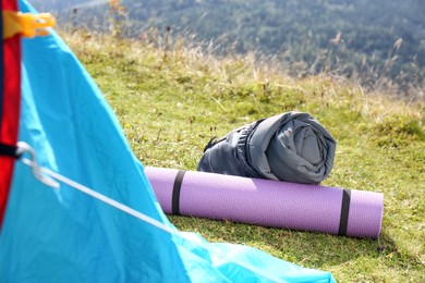 Photo of Sleeping bag and mat near camping tent outdoors