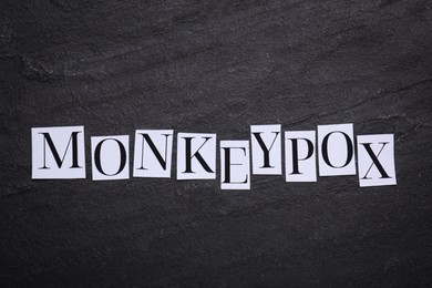 Word Monkeypox made of paper letters on black background, top view