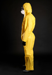 Man wearing chemical protective suit on black background. Virus research