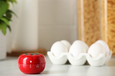 Kitchen timer in shape of tomato and eggs on white table. Space for text