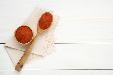 Photo of Bowl and spoon with aromatic paprika powder on white wooden table, flat lay. Space for text