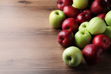 Fresh ripe red and green apples on wooden table, space for text