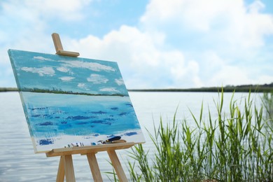 Wooden easel with unfinished painting near lake