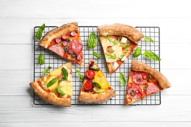 Slices of different delicious pizzas on white wooden table, flat lay