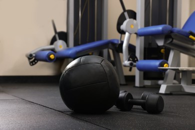Black medicine ball and dumbbells on floor in gym