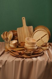 Photo of Set of wooden dishware and utensils on table against green background