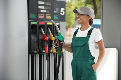 Young worker with fuel pump nozzle at modern gas station