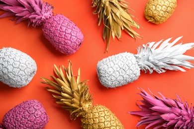 Photo of Many colorful pineapples on orange background, flat lay. Creative concept