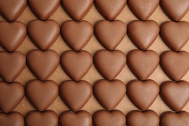Tasty heart shaped chocolate candies on brown background, flat lay. Valentine's day celebration