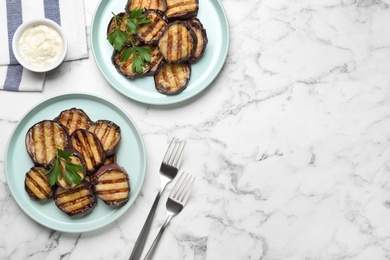 Delicious grilled eggplant slices and sauce on white marble table, flat lay. Space for text