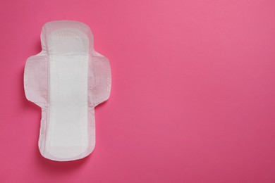 Sanitary napkin on pink background, top view. Space for text