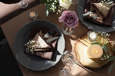 Photo of Festive table setting with beautiful tableware, candles and floral decor indoors, top view