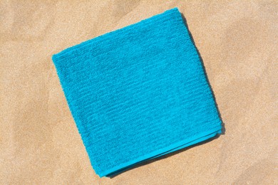 Soft blue beach towel on sand, top view