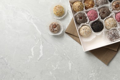 Different delicious vegan candy balls on light grey marble table, flat lay. Space for text