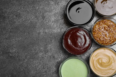 Many different sauces on grey table, flat lay. Space for text
