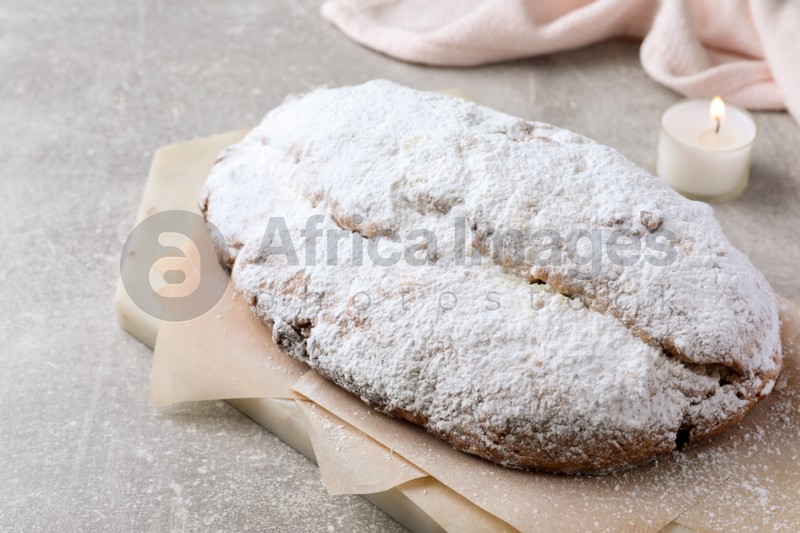 Delicious Stollen sprinkled with powdered sugar on light table, closeup