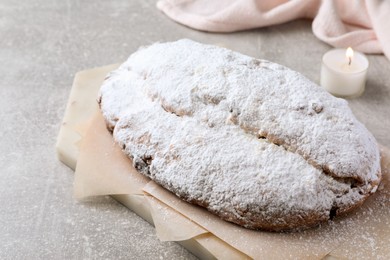 Delicious Stollen sprinkled with powdered sugar on light table, closeup