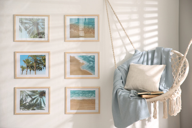 Different pictures on wall and hanging chair in room. Artworks in interior design