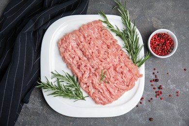 Raw chicken minced meat with rosemary and spices on grey table, flat lay