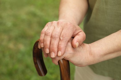 Elderly woman with walking cane outdoors, closeup